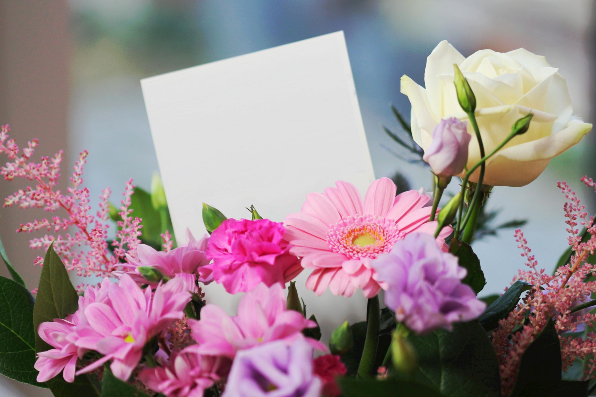 A bouquet of pink and purple flowers with a card in the middle.