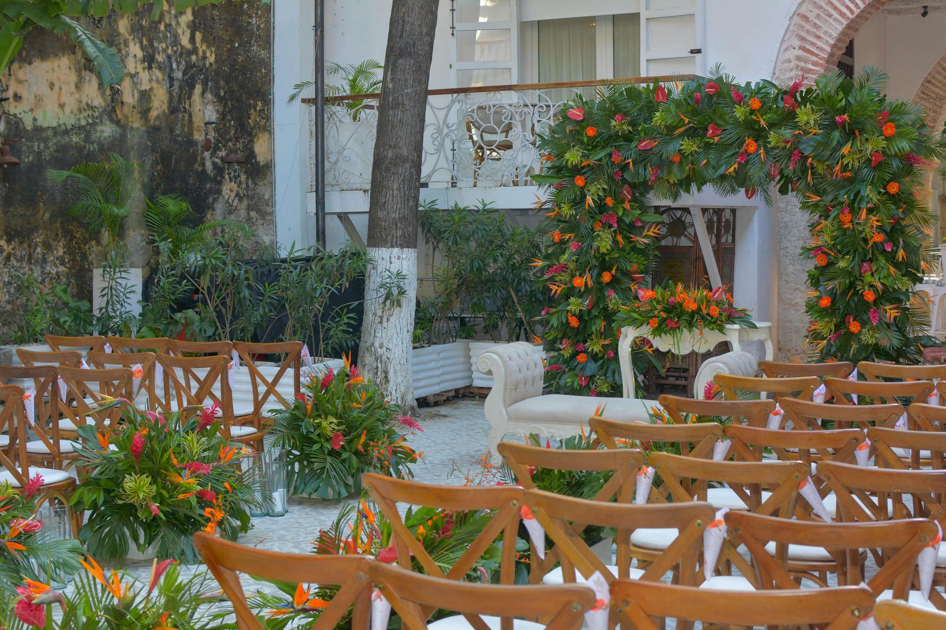 A row of wooden chairs are lined up in front of a building decorated with flowers.