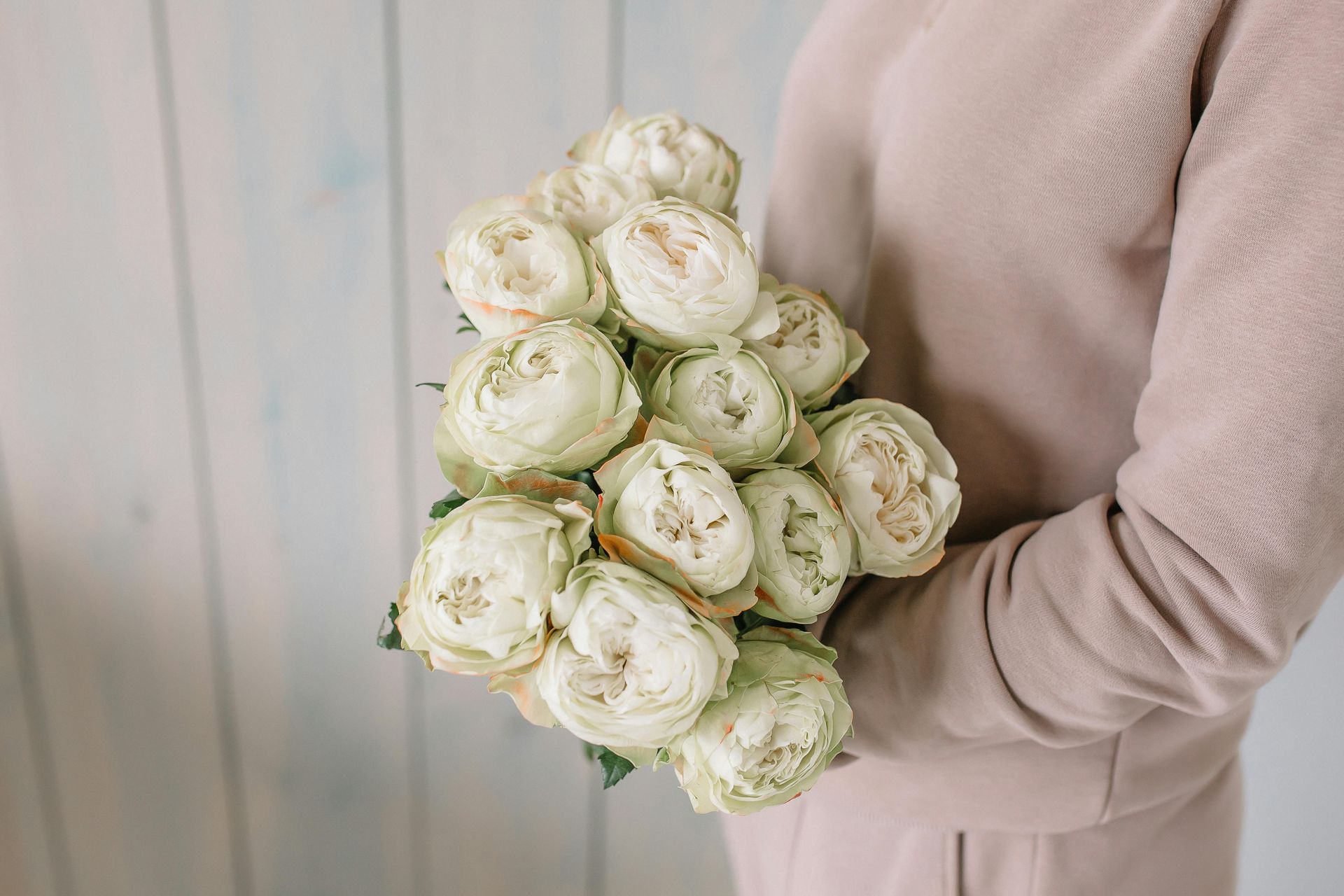 A woman is holding a bouquet of white roses in her hands.