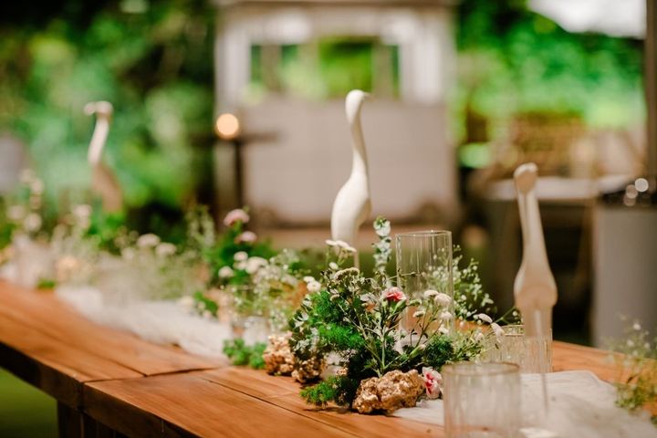 A long wooden table with flowers and birds on it.