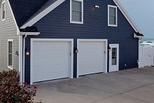 A blue house with white garage doors and a white fence.