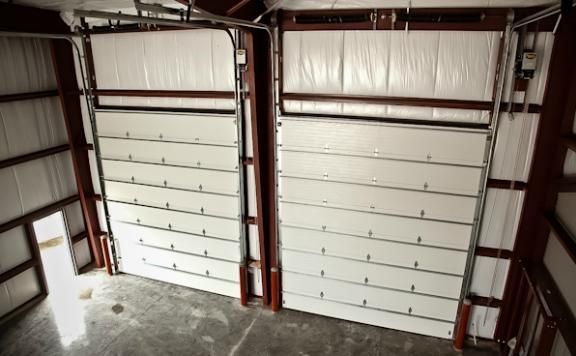 Two white garage doors are open in a building