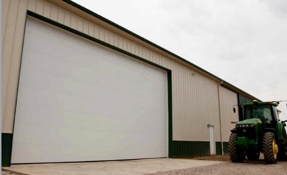 A green tractor is parked in front of a white building