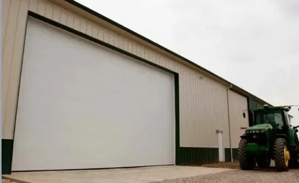 A green tractor is parked in front of a white building.