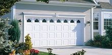 A white garage door is sitting in front of a house.