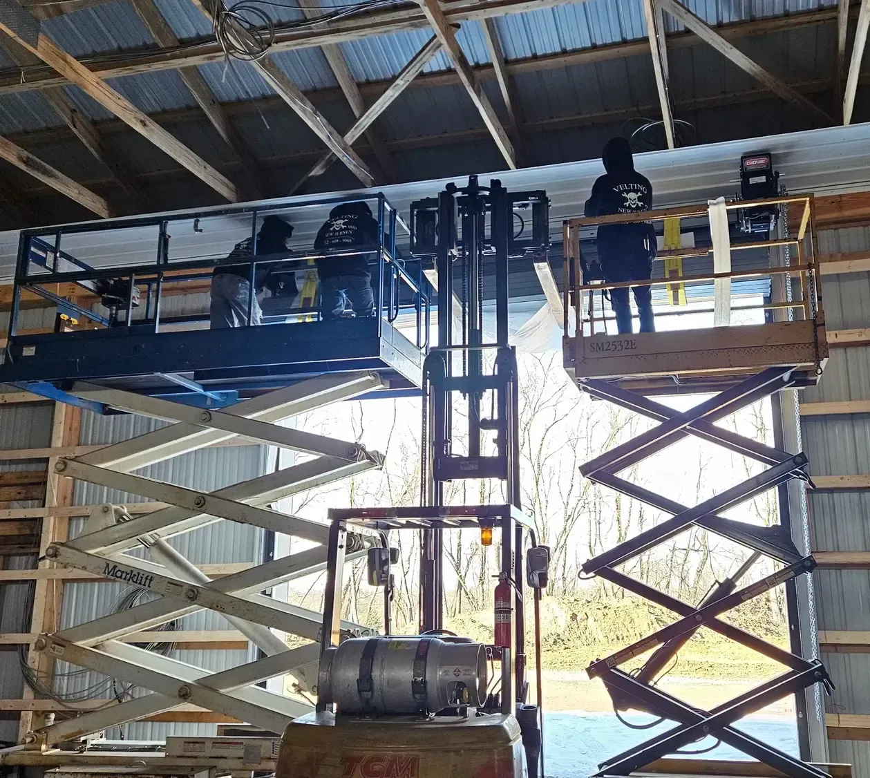 A man is standing on a scissor lift in a warehouse.