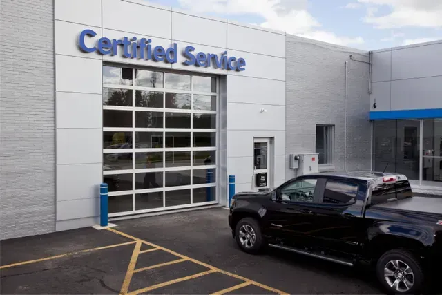 A black truck is parked in front of a certified service building