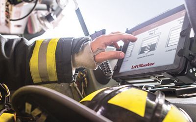 A firefighter is using a tablet computer while wearing a helmet.