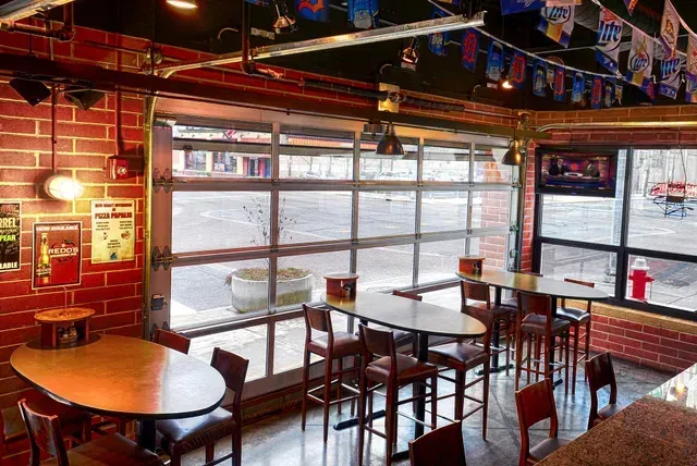 A restaurant with tables and chairs in front of a garage door.