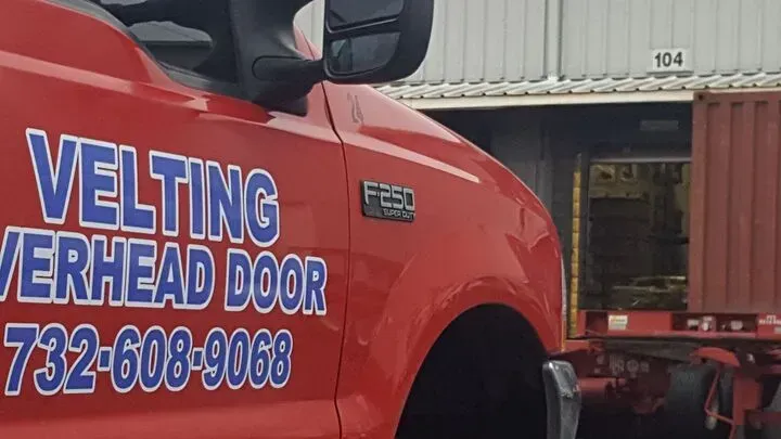 A red truck with velting overhead door written on the side