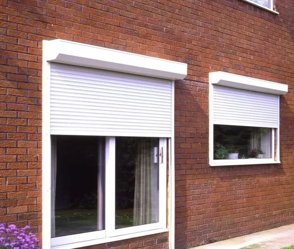 A brick building with two windows with white shutters on them