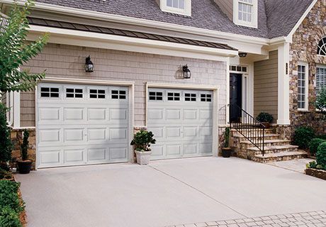 A house with two white garage doors and stairs in front of it.