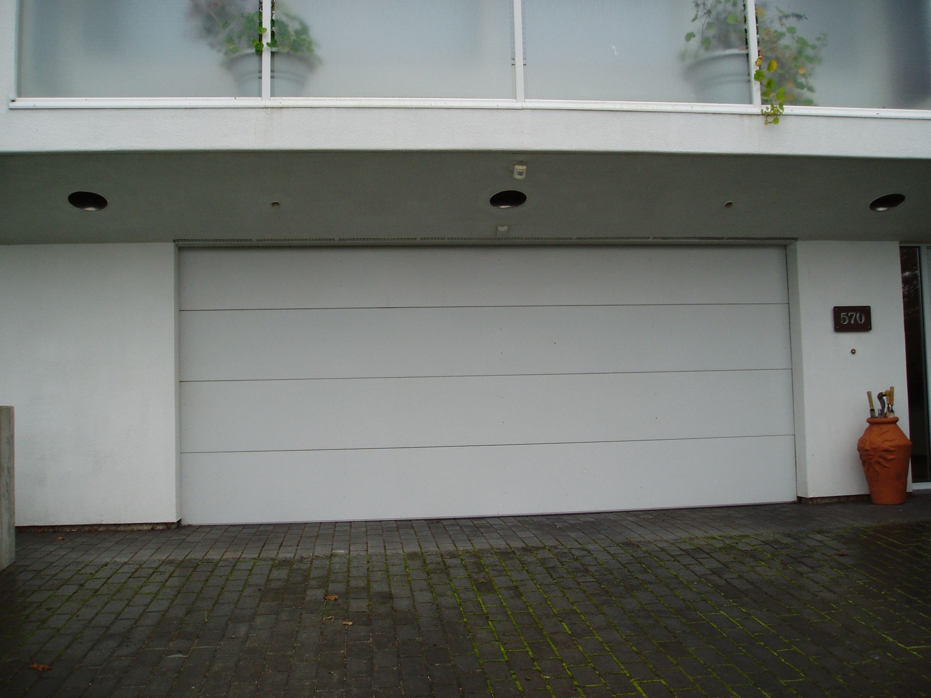 A white garage door is sitting in front of a white building.