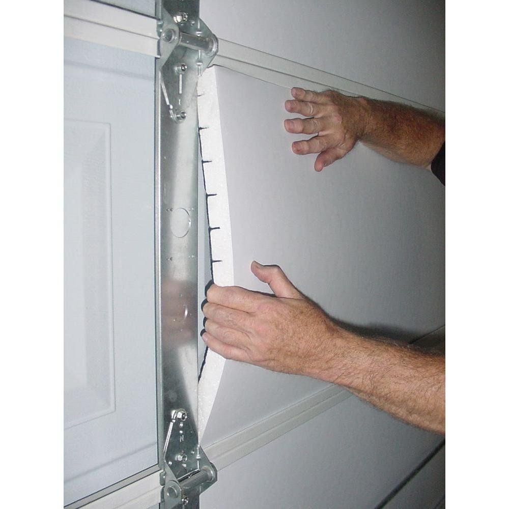 A person is holding a piece of styrofoam over a garage door