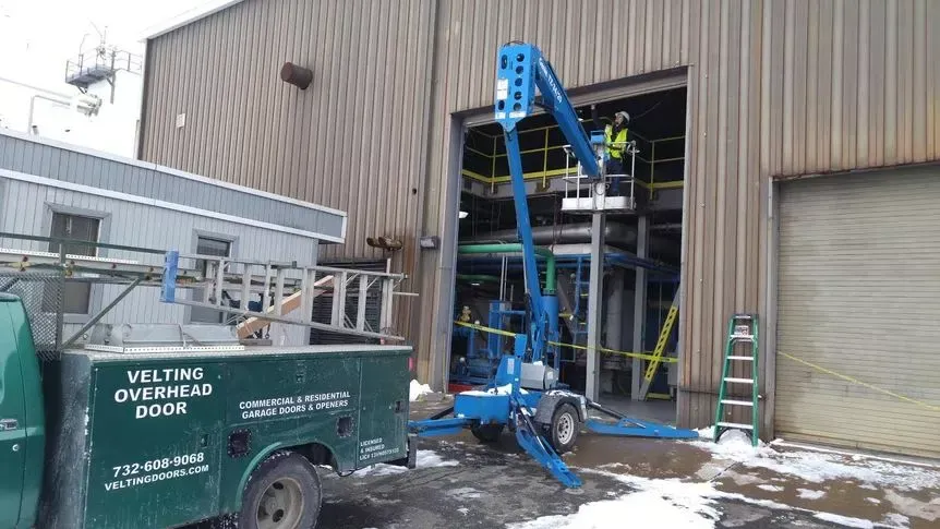 A green utility truck is parked in front of a building.