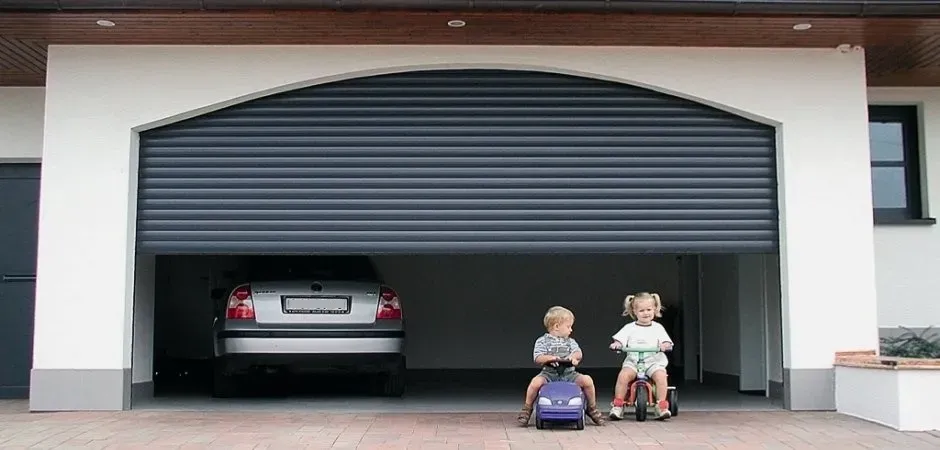 Two children are playing in a garage with a car parked in it