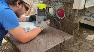 A man is using a router to cut a piece of wood.