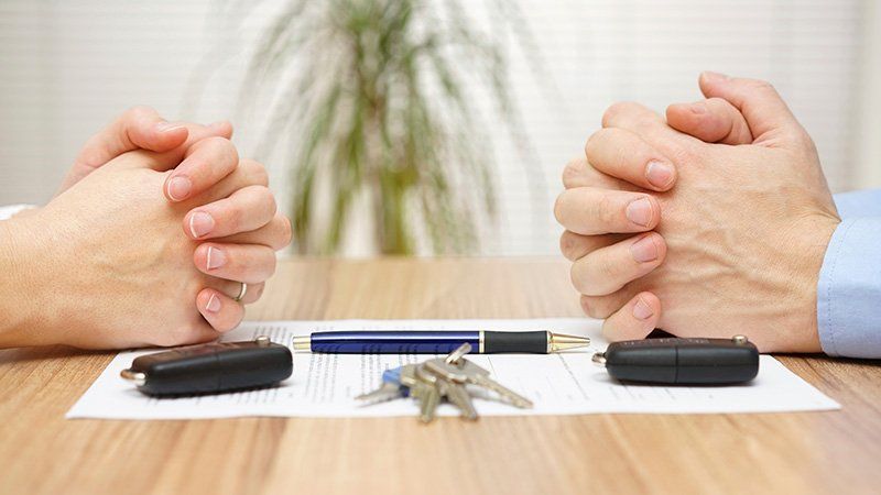 two people's hands on a table next to keys and a pen
