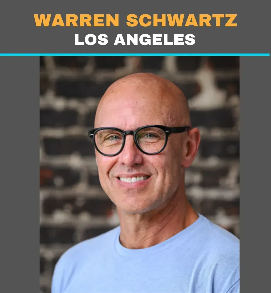 Portrait of Warren Schwartz in Los Angeles, smiling in glasses against a blurred brick background