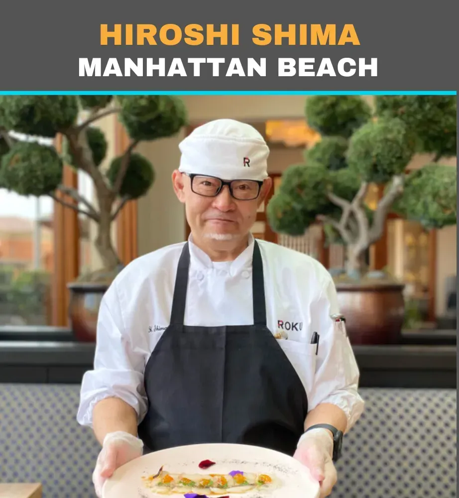 Chef Hiroshi Shima holding a plated dish at Manhattan Beach restaurant, wearing white chef’s coat and apron