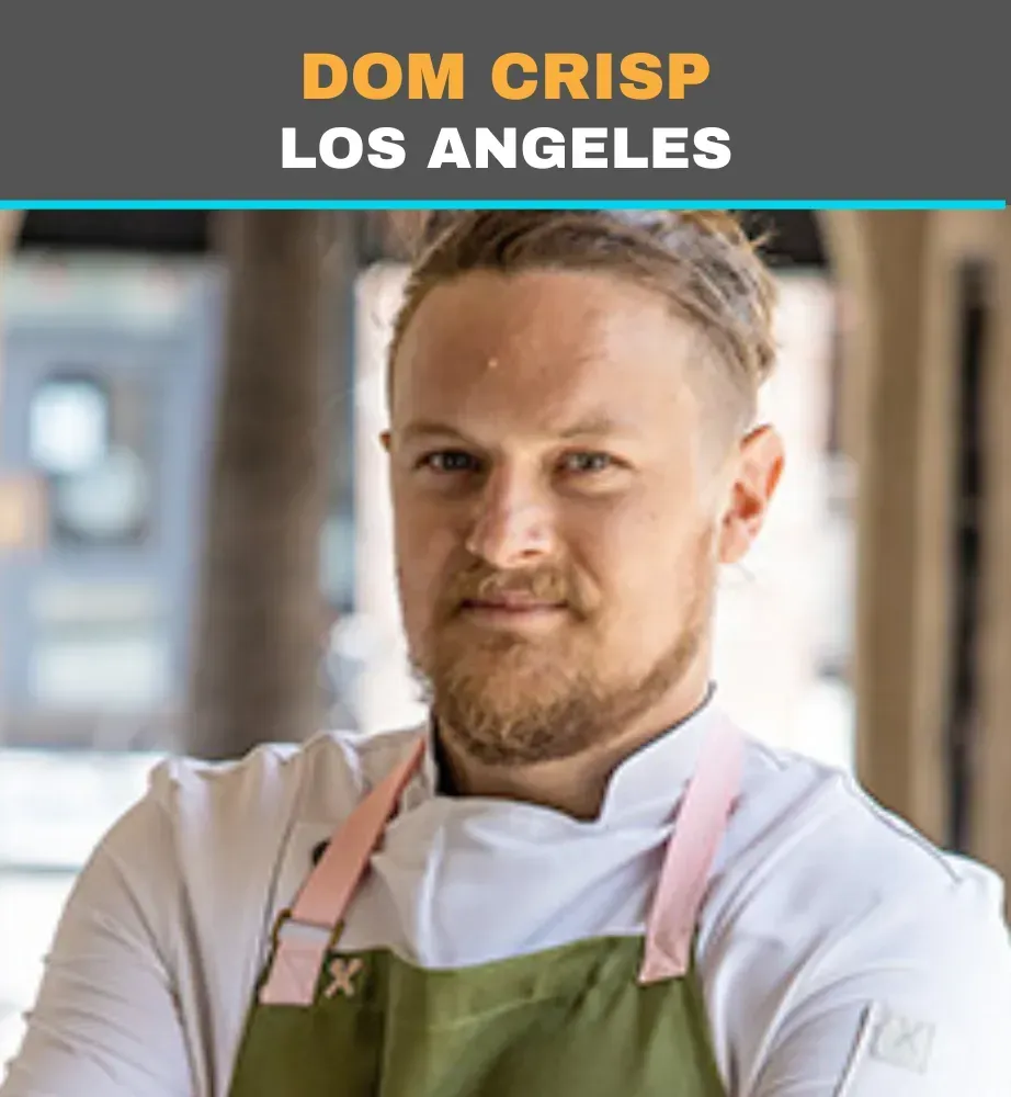Chef in white uniform and green apron, labeled “Dom Crisp, Los Angeles,” looking at the camera.