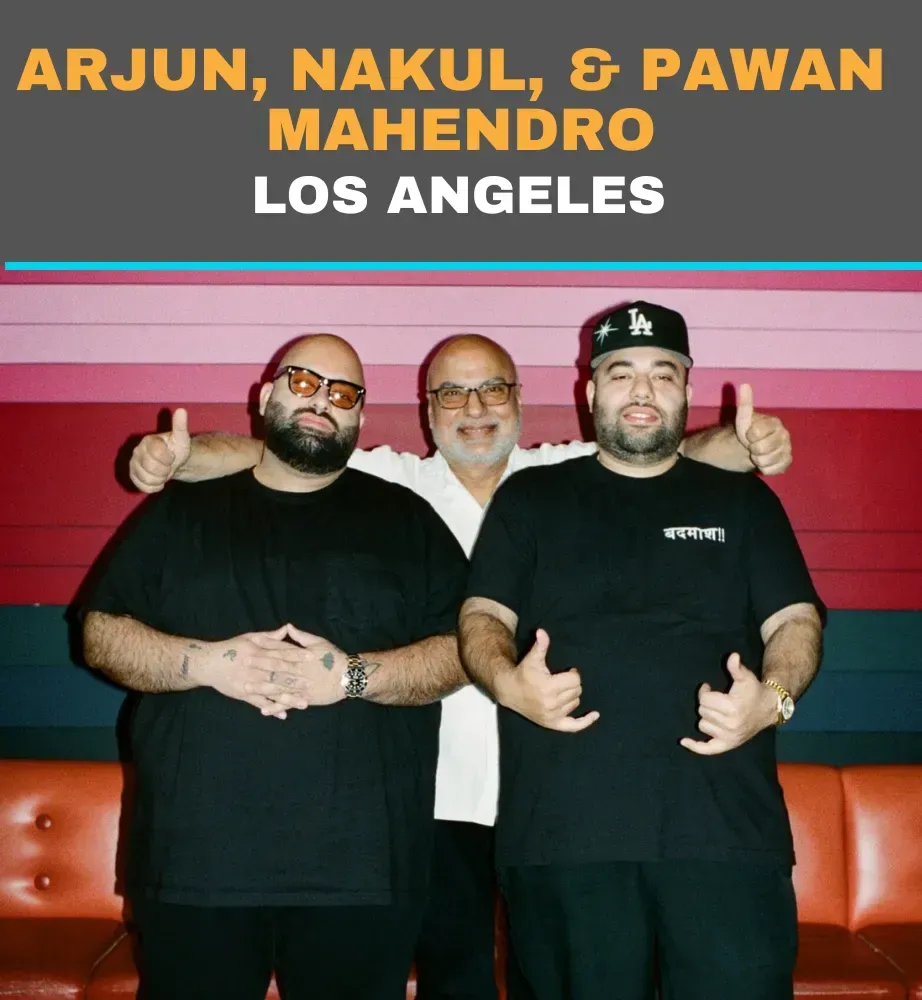 Arjun, Nakul, and Pawan Mahendro posing in black shirts at a Los Angeles venue
