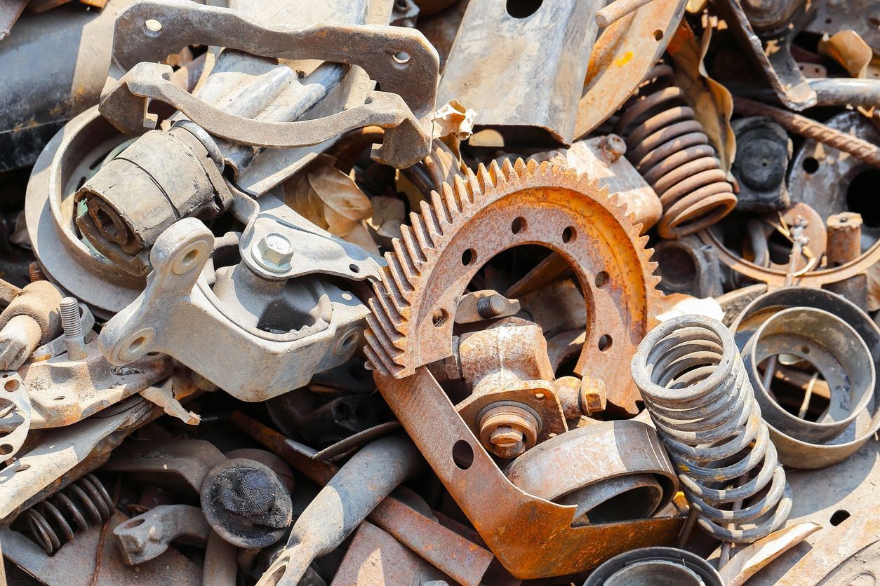 Pile of rusty metal parts, including gears, springs, and other vehicle components.