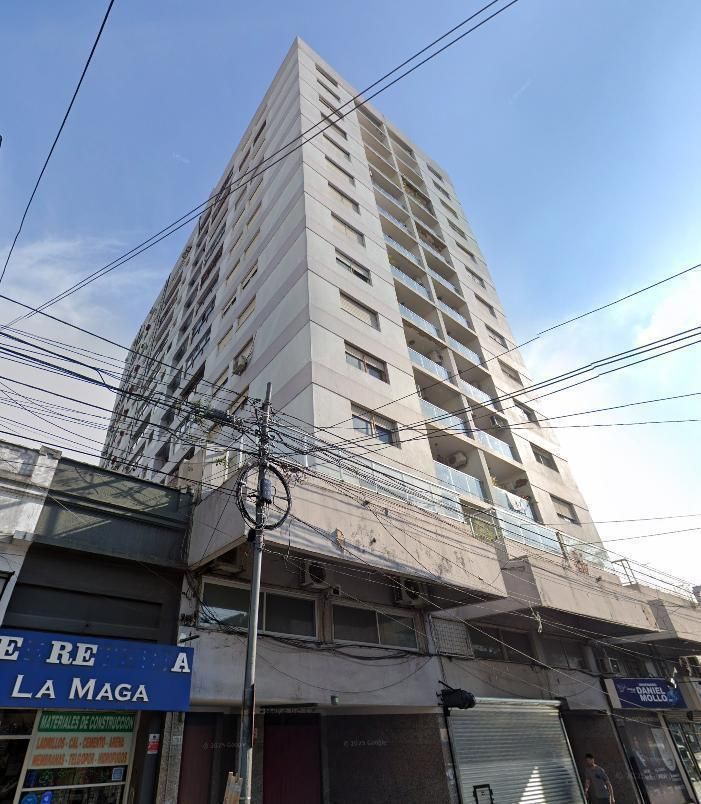 Edificio de apartamentos alto de color beige con locales comerciales en la planta baja 