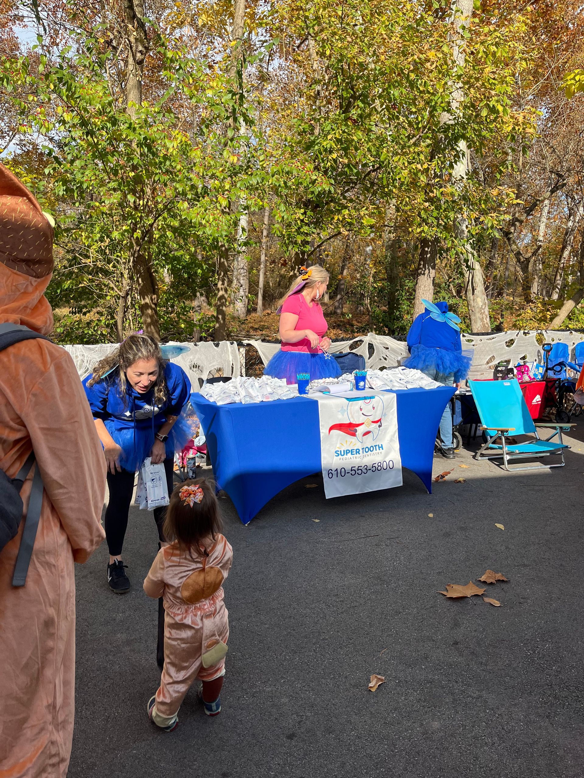 A little girl in a bear costume is standing in front of a table.