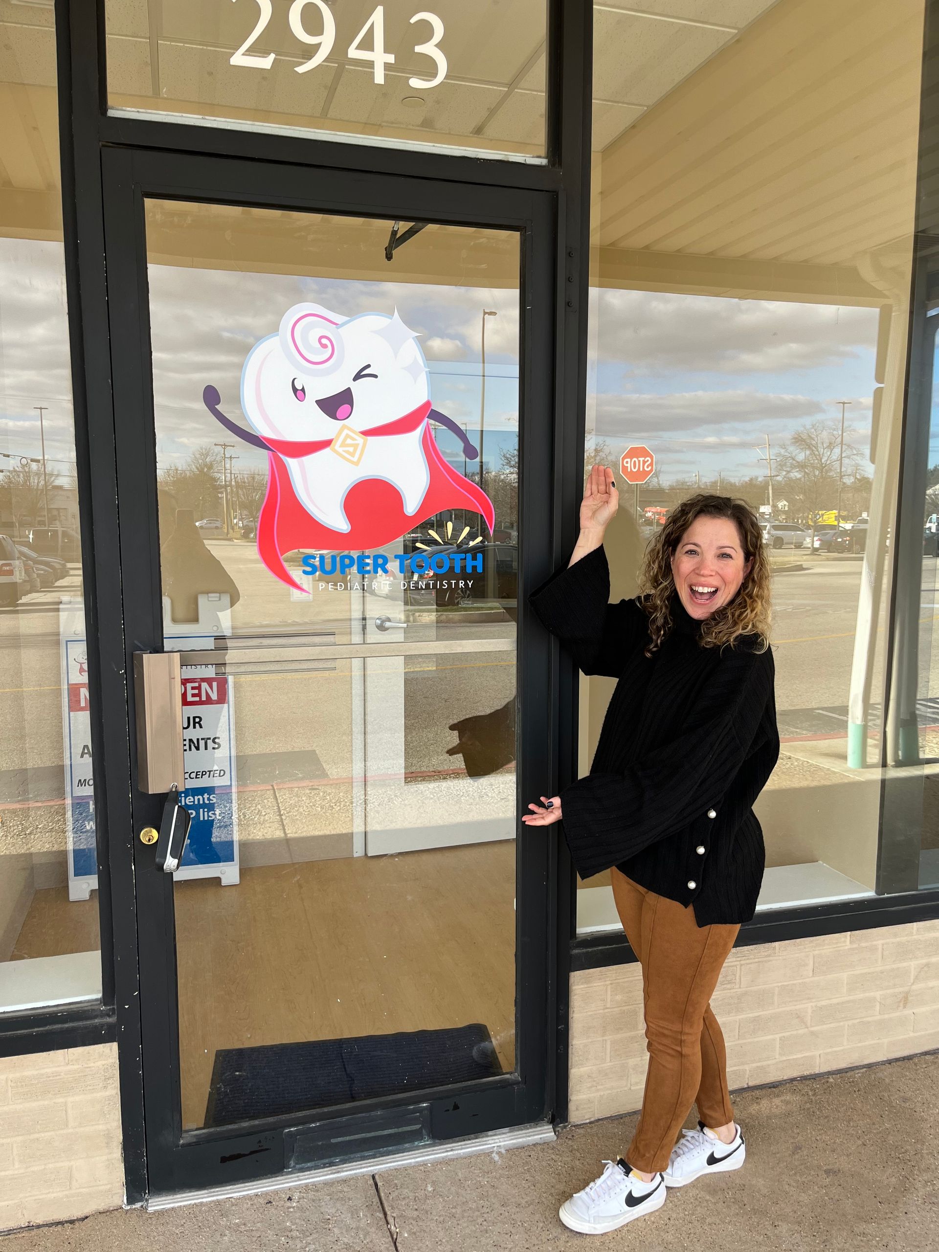 A woman is standing in front of a door with a picture of a tooth on it.