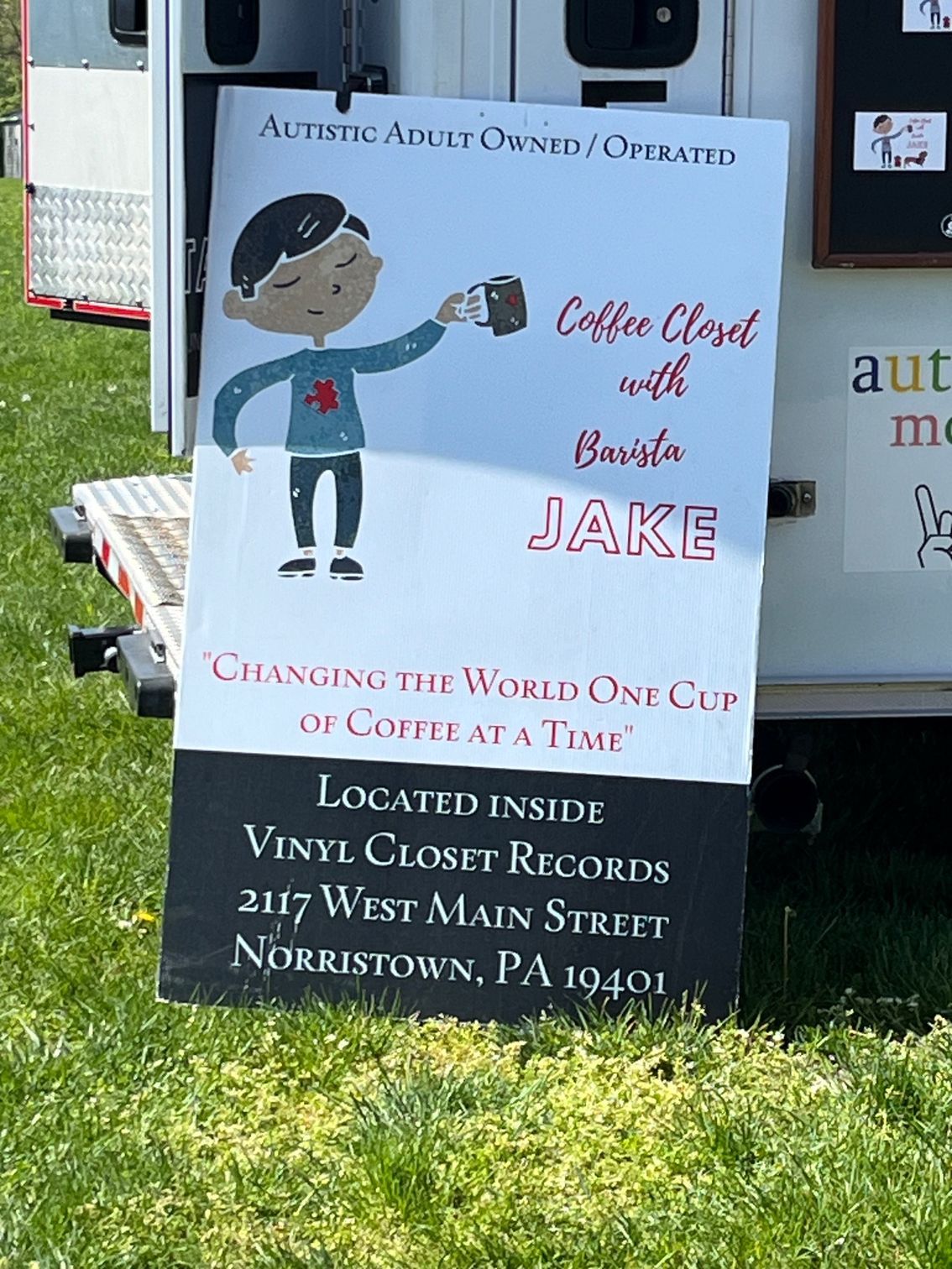 A sign that says `` coffee closet with barista jake '' is sitting in the grass.