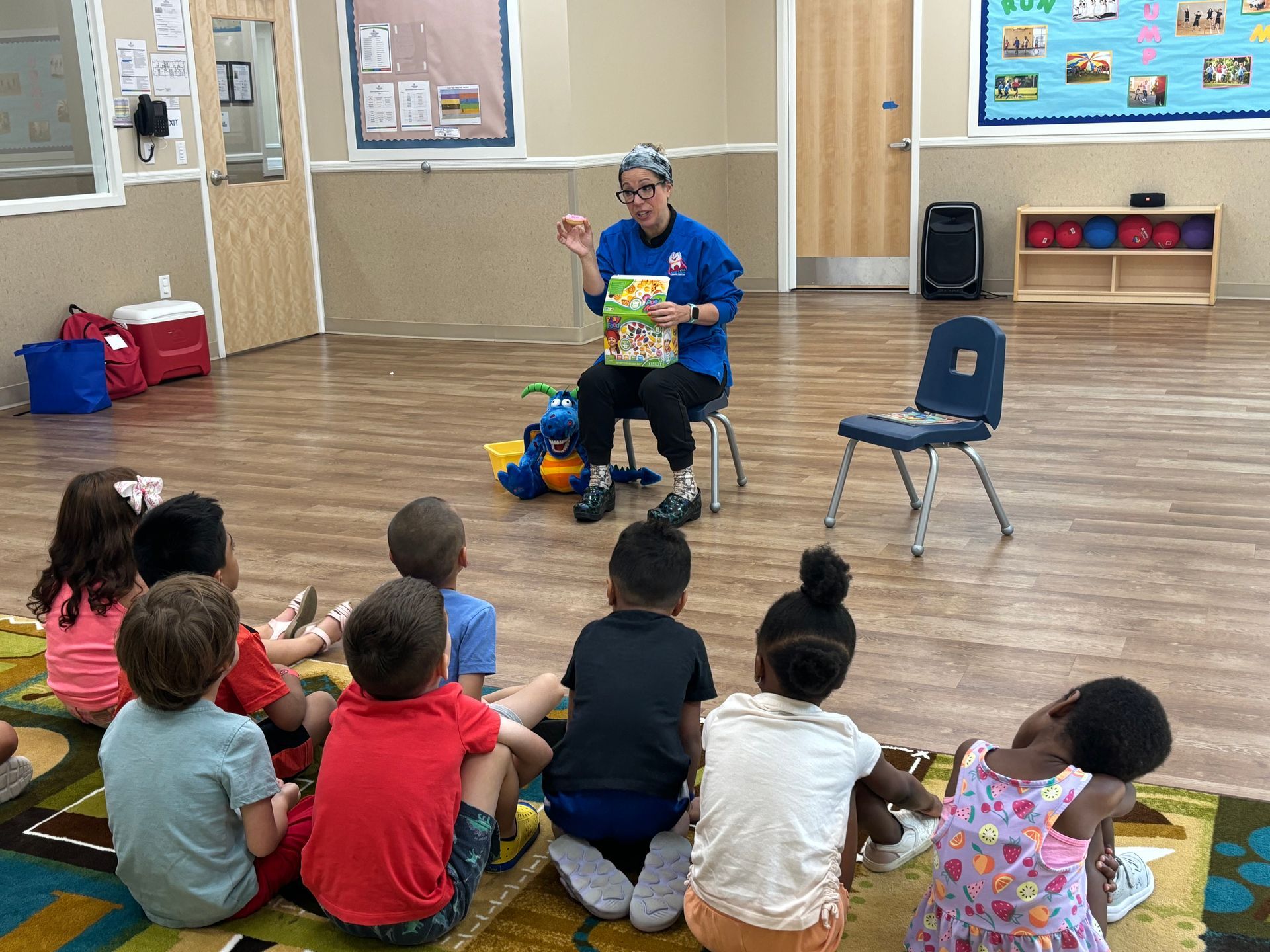 A woman is sitting on the floor reading a book to a group of children.