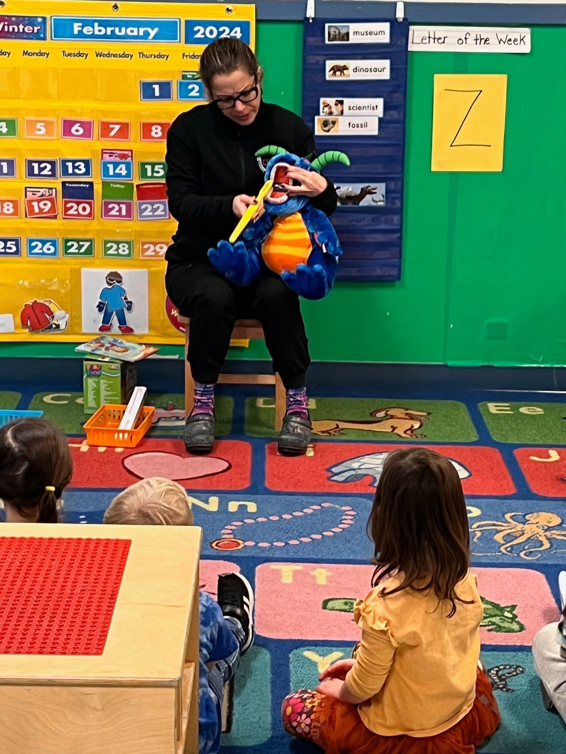 A woman is reading a book to a group of children in a classroom.