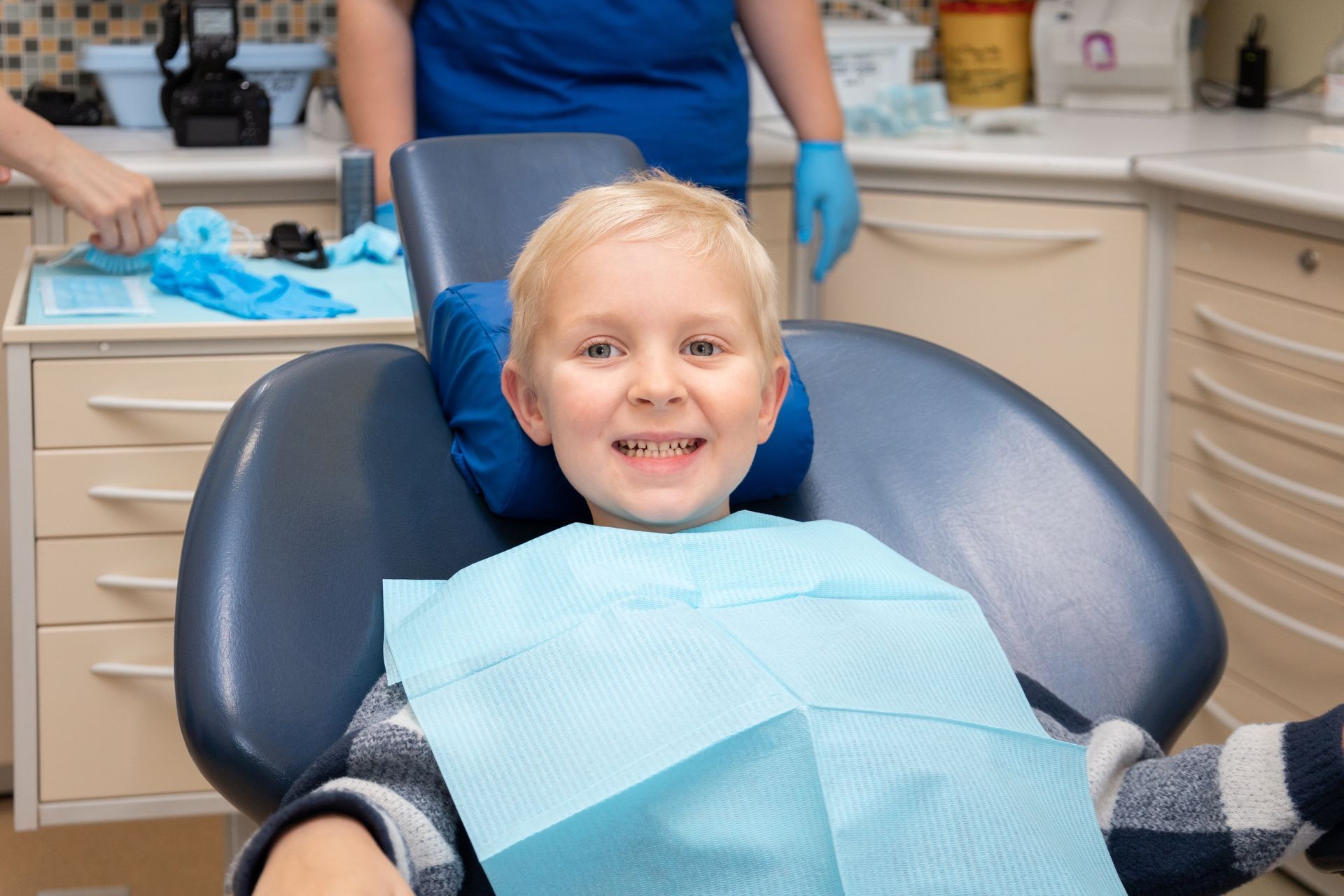 A young boy is sitting in a dental chair and smiling.