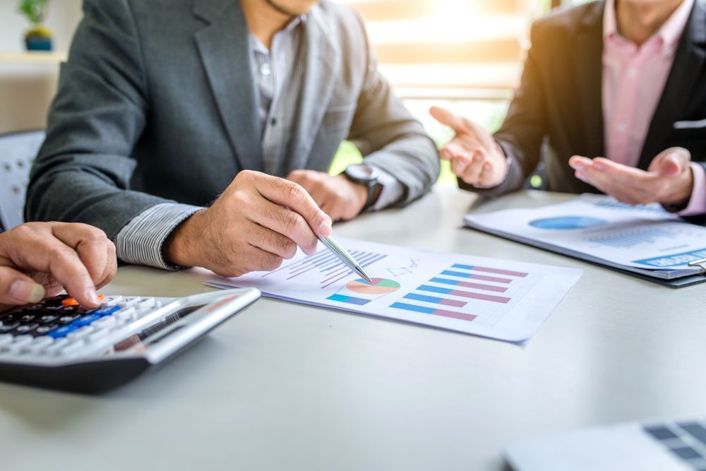 Business People Analyse Charts and Use a Calculator at a Table — Accountsloop Tax & Business Advisory in Geelong, VIC