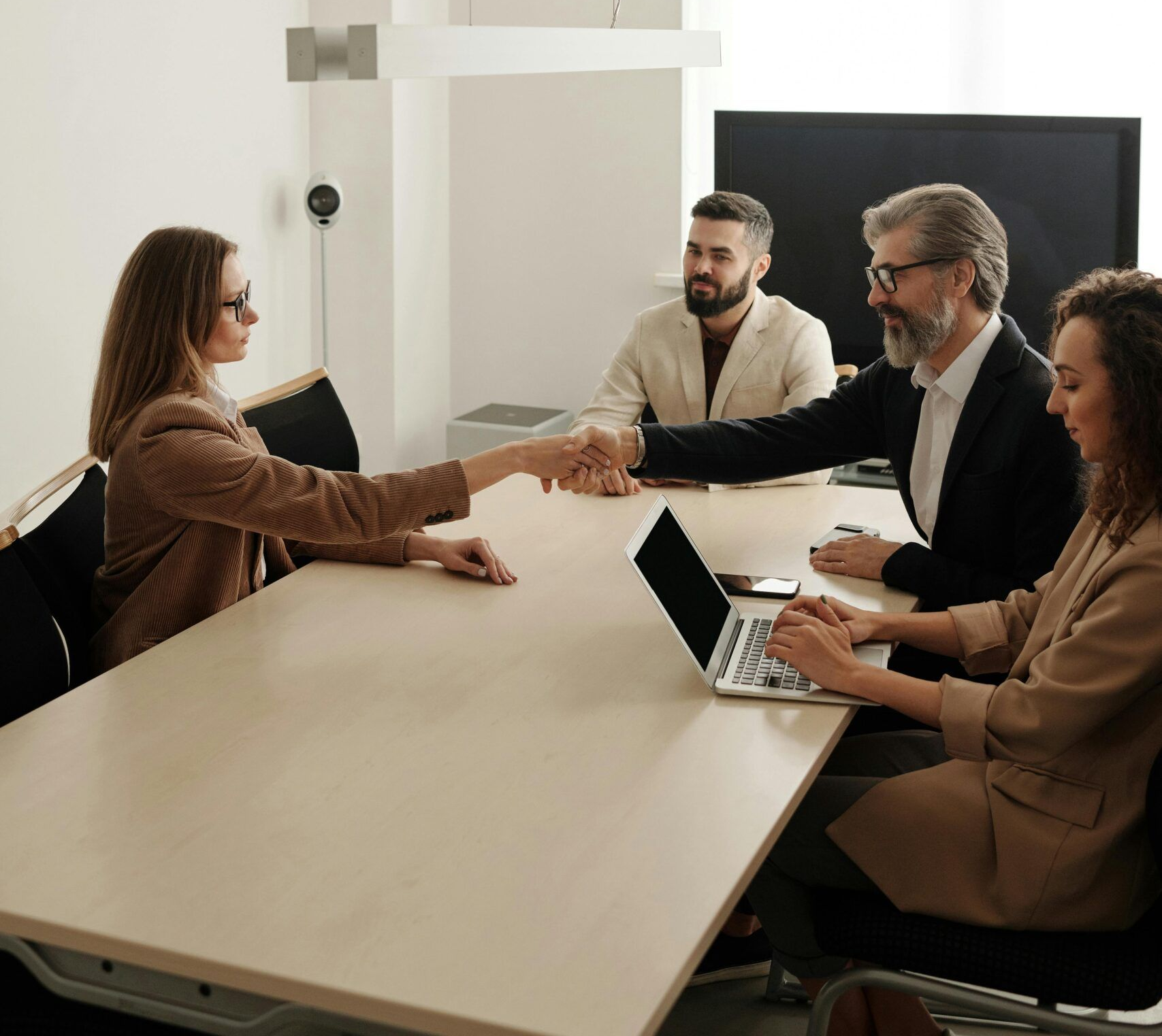 Four People in a Meeting Room, Woman Shakes Hands With a Man, Another Person Types on Laptop — Accountsloop Tax & Business Advisory in Geelong, VIC