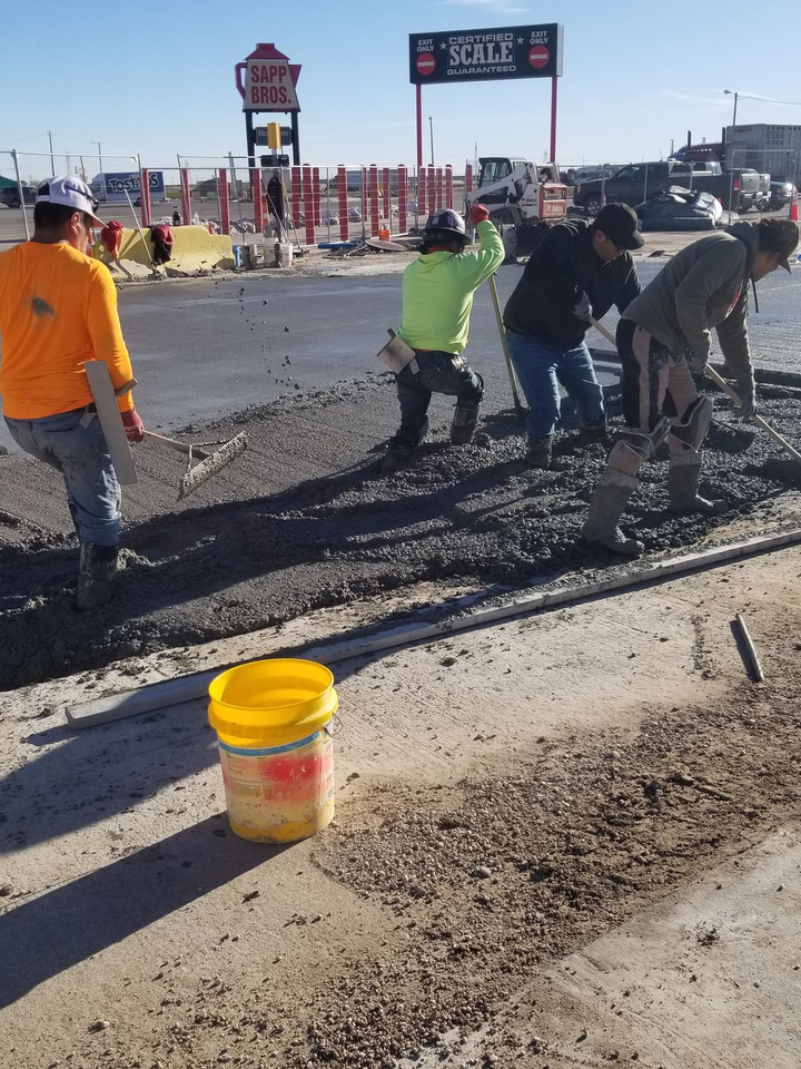 A group of construction workers are working on a concrete driveway.