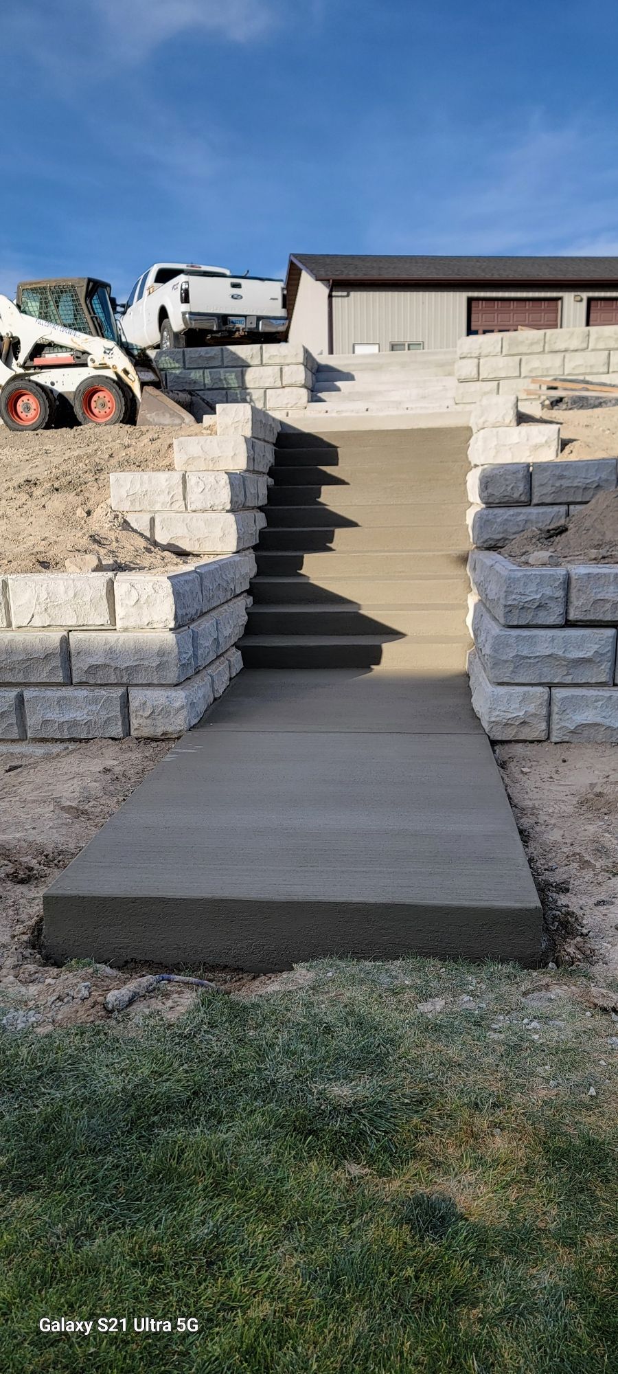 A person is working on the sidewalk in front of a house.