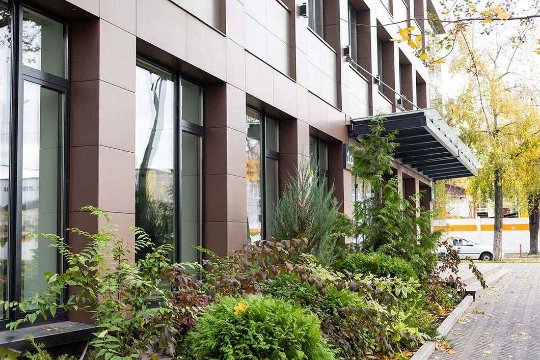 A large building with lots of windows and plants in front of it.