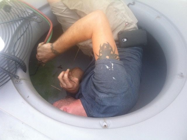 Person inside a large, round container, working with wires.