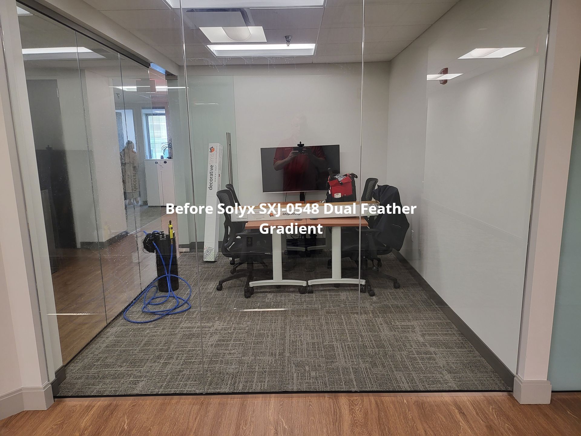 A conference room with a glass wall and a table and chairs.