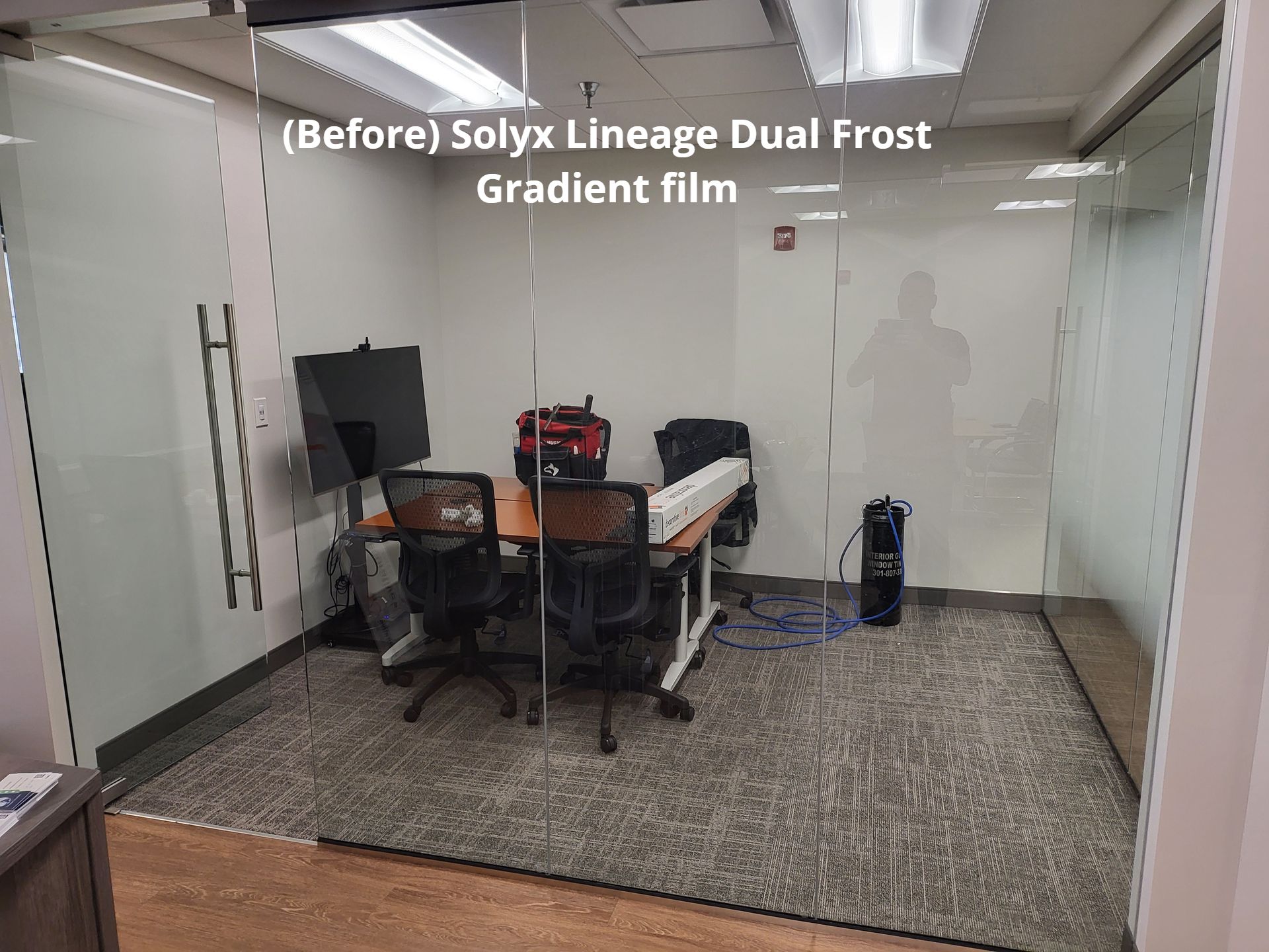 A conference room with a desk , chairs and a computer.