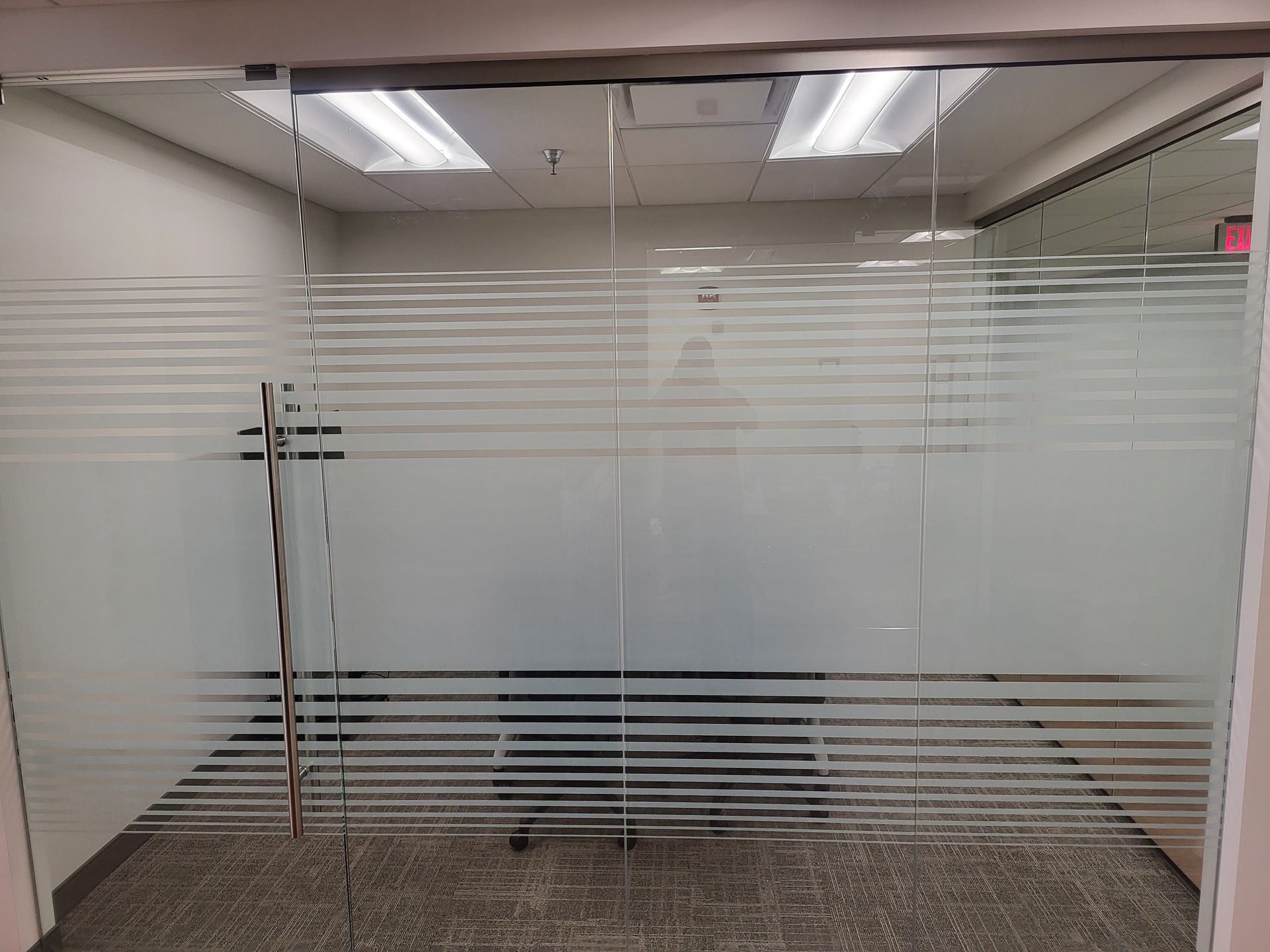 A conference room with a glass wall and sliding glass doors.