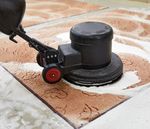 A person is cleaning a rug with a machine.