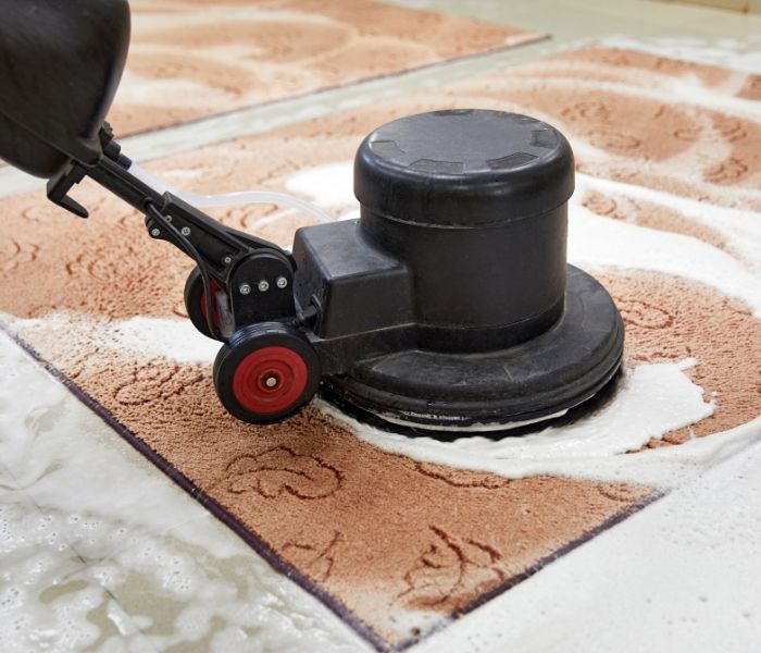 A person is cleaning a rug with a machine.