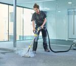 A woman is cleaning a carpet with a vacuum cleaner.