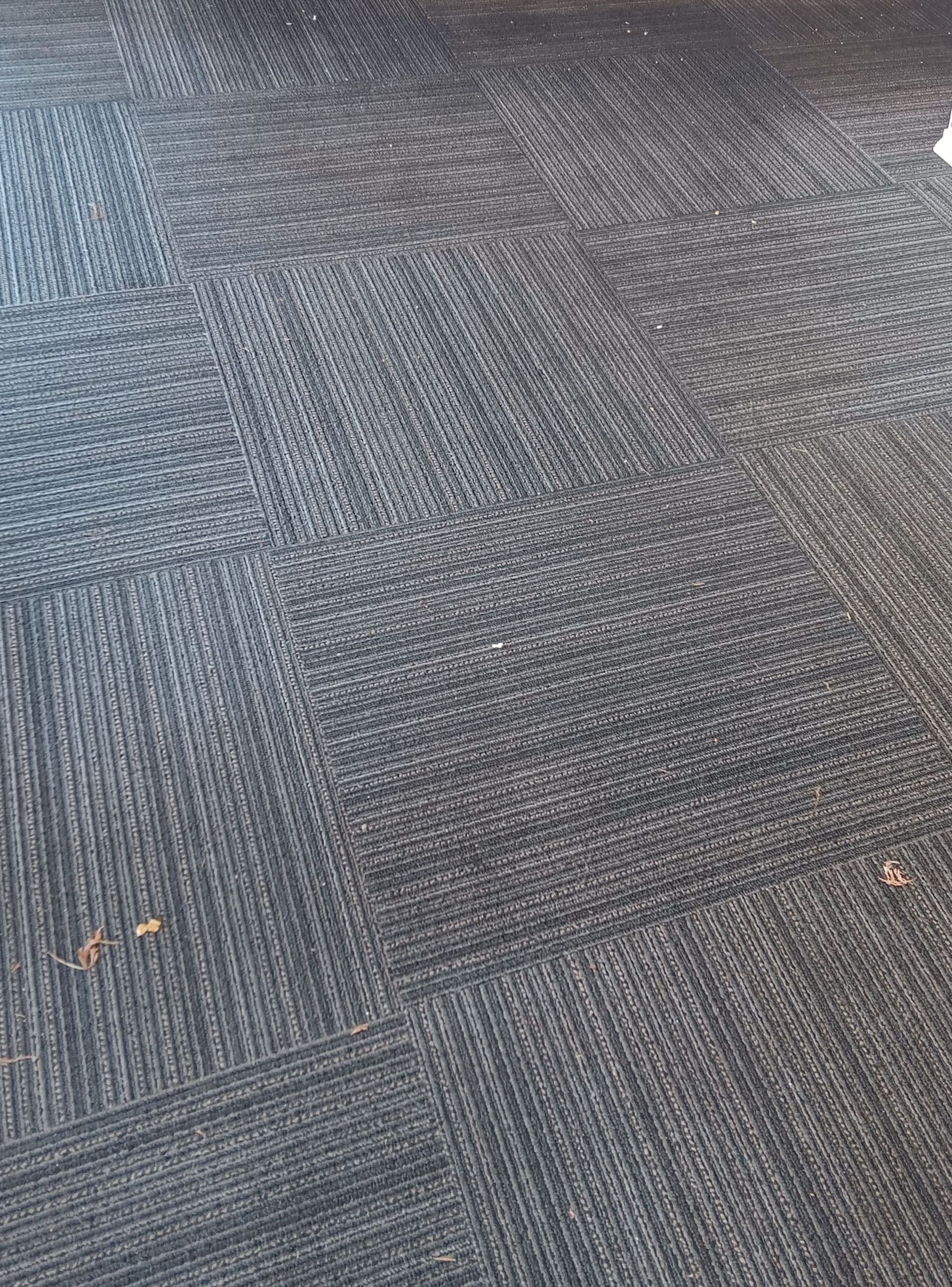 A close up of a black carpeted floor with a pattern.