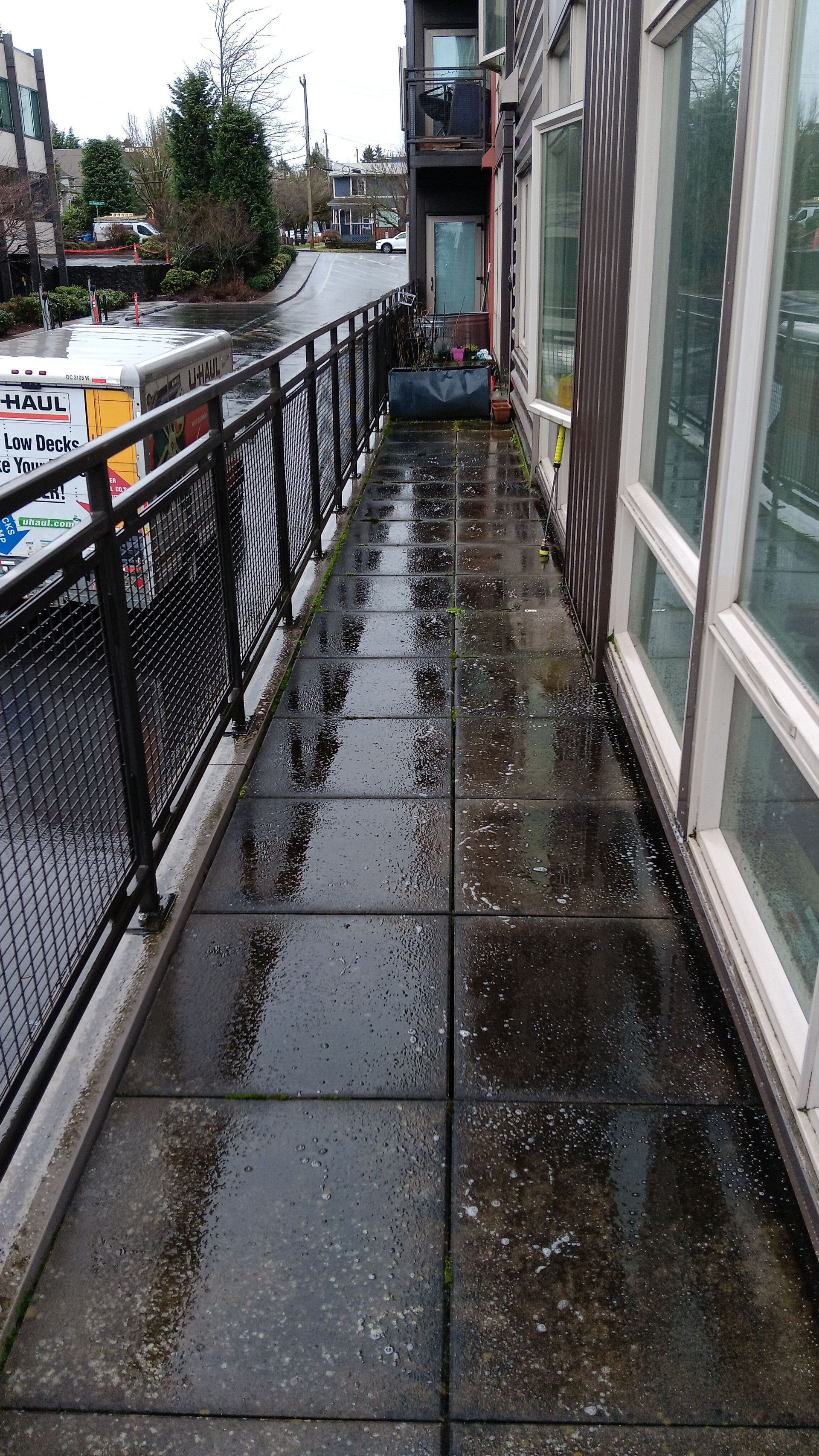A dirty sidewalk next to a building with a balcony.