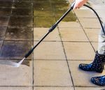 A person is using a high pressure washer on a tiled floor