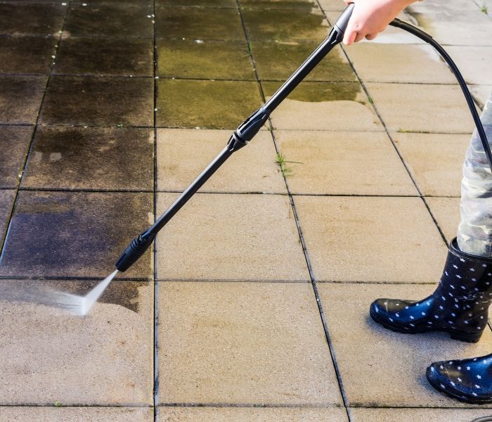 A person is using a high pressure washer on a tiled floor